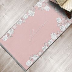 a pink rug with white flowers on it and an open book sitting next to it