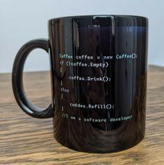 a black coffee mug sitting on top of a wooden table