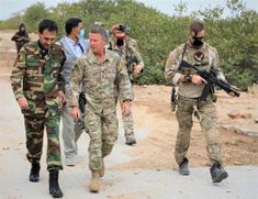 men in camouflage walking down a dirt road