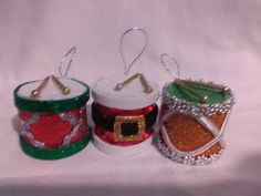 three christmas candles are sitting next to each other on a white cloth covered tablecloth