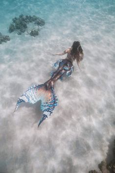 a woman is swimming in the ocean with a mermaid tail