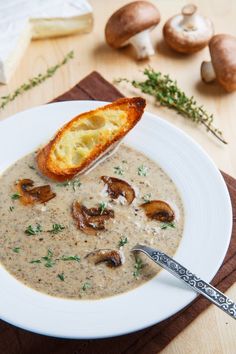 a white plate topped with mushroom soup and bread