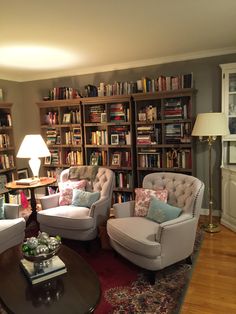 a living room filled with furniture and bookshelves covered in lots of bookcases