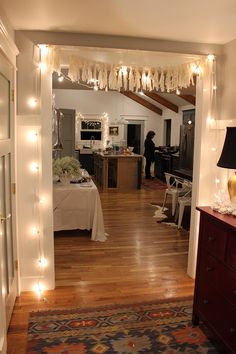 a living room filled with furniture next to a kitchen and dining room table covered in lights