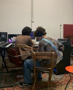 two men sitting at desks with computers in front of them, one playing the keyboard