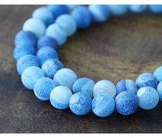 blue and white marble beads on a wooden surface with the bead cord down to it's end