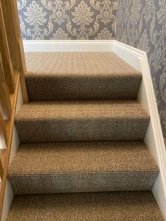 carpeted stairs leading up to a wall with damask on the walls behind them