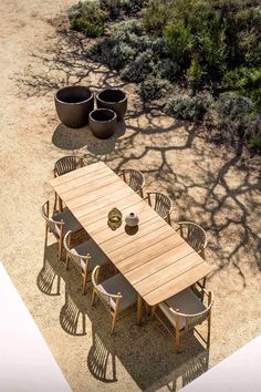 an aerial view of a table and chairs in the middle of a dirt area with trees