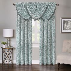 a living room with a couch, chair and window covered in blue floral curtain panels