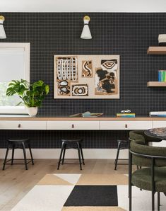 a black and white checkered wall in a room with two green chairs, a desk and shelves