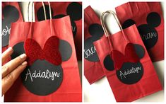 a hand is holding up a red bag with mickey mouse ears on it and the words add