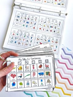 a person holding two cards in front of a binder that has pictures on it