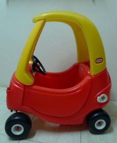 a little red toy car sitting on top of a white floor next to a wall