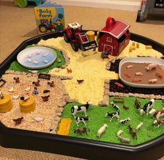 a play tray filled with farm animals and toys