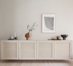 a white cabinet with two vases on top of it next to a framed photograph