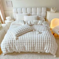 a bed with white sheets and pillows in a room