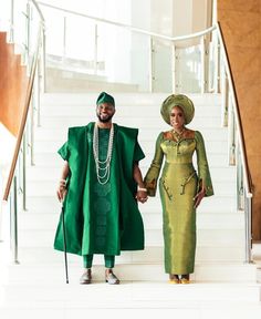 a man and woman dressed in green holding hands