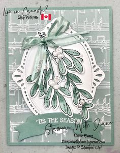 a card with an ornament and ribbon on the front, featuring green leaves