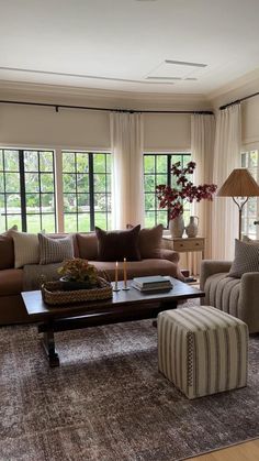 a living room with couches, chairs and coffee table in front of large windows