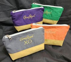 four different colored zippered pouch bags sitting on a black cloth covered table with the words crown royal xo written in gold