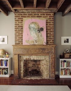 a living room with a fire place and bookshelves on the wall, along with a painting