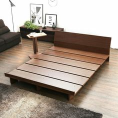 a wooden bed frame sitting on top of a hard wood floor next to a couch