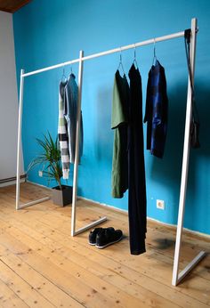 an empty room with clothing hanging on clothes racks and shoes in front of the wall