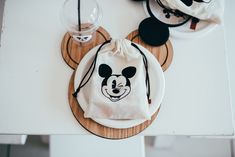 mickey mouse drawstring bag sitting on top of a white table next to two cups