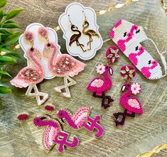 pink flamingo earrings and brooches are sitting on a table