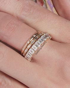 a woman's hand with two gold rings on top of her finger and the ring has three baguettes in each band