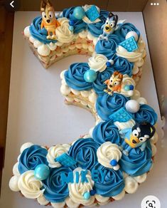 a cake shaped like the number six with blue frosting and cartoon characters on it