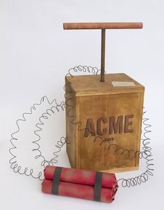 an old wooden box with a stick sticking out of it next to a red tube