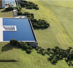 an aerial view of a house in the middle of a green field with water and trees