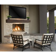 two chairs sitting in front of a fire place with a flat screen tv above it