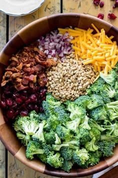 a bowl filled with broccoli, cranberries, cheese and other foods