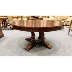 an oval wooden table with two leaves on the top and four legs, in front of chairs