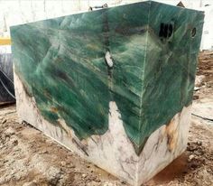 a large green marble block sitting on top of dirt