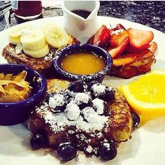 french toast with fruit and powdered sugar on the side, along with dipping sauce