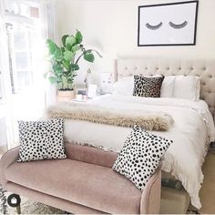 a white bed with black and white pillows on top of it next to a window