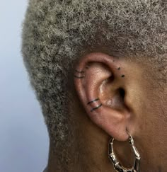 a close up of a person's ear with piercings on the top of their ears