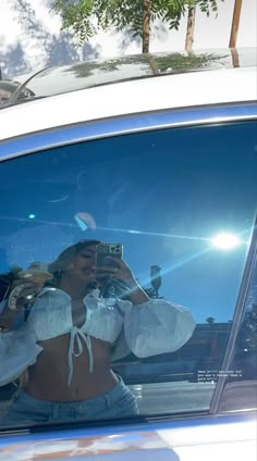 a woman taking a selfie in the back window of a car