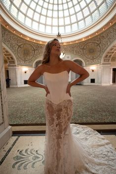 a woman in a white wedding dress standing on the floor with her hands on her hips