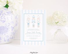 there is a blue and white vase with flowers in it next to a card on a table