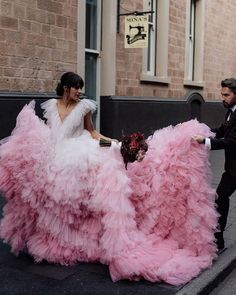 a man in a tuxedo walking next to a woman in a pink dress