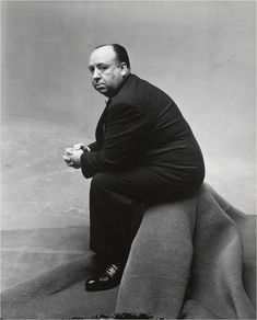 an old photo of a man sitting on top of a large chair with his hands clasped