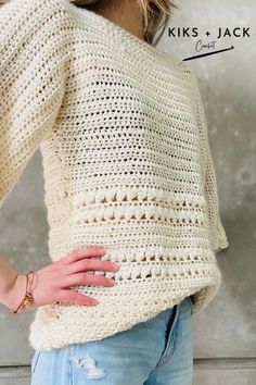 a woman wearing a white crochet sweater with her hands on her hip and the back of her body