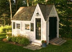 a small white shed sitting in the grass