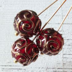 three red and gold bead earrings sitting on top of each other