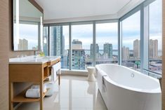 a bathroom with a large bathtub sitting next to a window filled with tall buildings