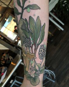 a person with a tattoo on their arm and leg is holding onto a green plant